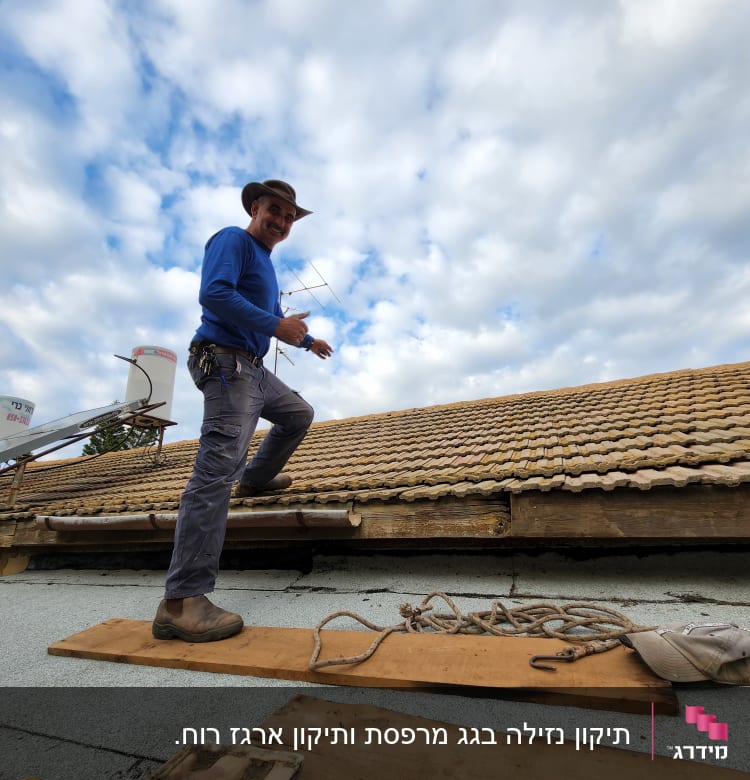 אדם עומד על גג רעפים עם קרשים וחבלים